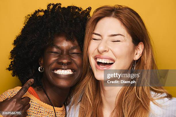 diverse women friends laughing together on yellow background - side by side stock pictures, royalty-free photos & images