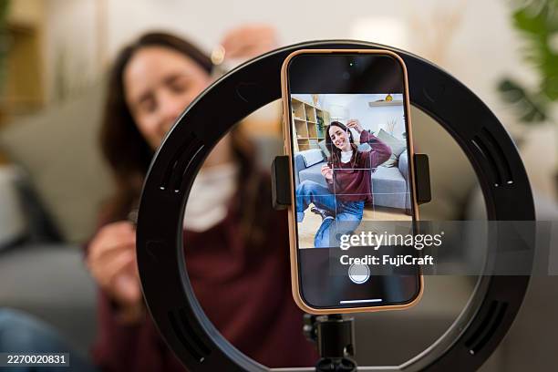 giovane donna adulta che registra video con smartphone e luce ad anello - social media marketing foto e immagini stock