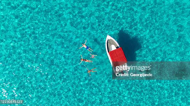 family swimming near rented boat in crystal clear sea - aegean sea stock pictures, royalty-free photos & images