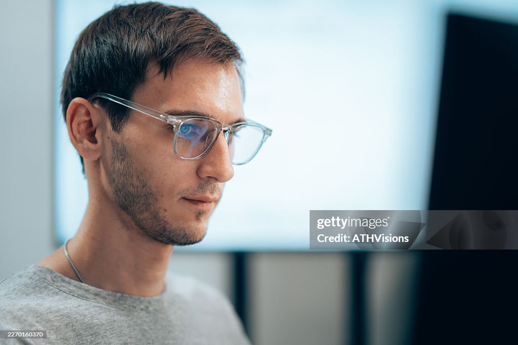 Male Software Developer Coding at Computer Workstation