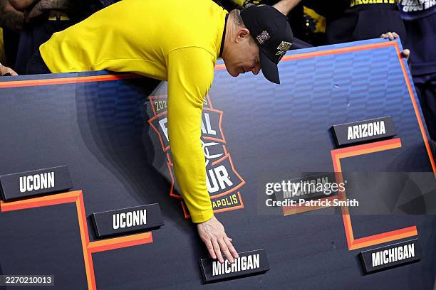 Head coach Dusty May of the Michigan Wolverines places the Michigan name on the championship bracket after defeating the UConn Huskies, 69-63, in the...