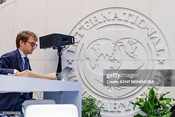 Person works on his laptop in the atrium of the International Monetary Fund building during the first day of the 2026 Spring Meetings of the IMF and...