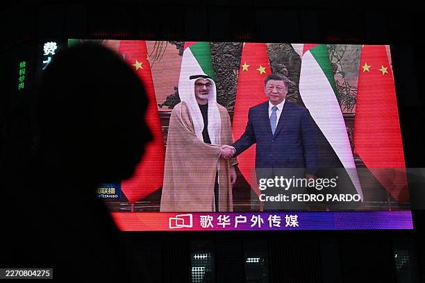 News footage on a giant screen outside a shopping mall shows China's President Xi Jinping meeting with Abu Dhabi's Crown Prince Sheikh Khaled bin...