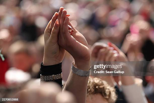 People hold hands as a show of unity as they listen to Peter Magyar, lead candidate of the Tisza party, speak on his last day of election campaign...