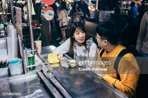 A young Asian couple visited a famous local night market and tasted street food in Taiwan A young Asian couple visited a famous local night market and tasted street food in Taiwan