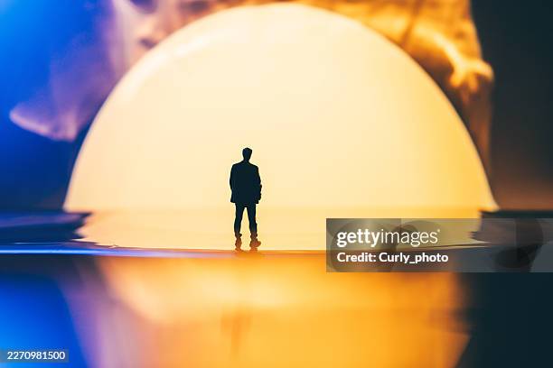 a silhouette of a man stands before a massive glowing sphere, reflected on a glossy surface. - sun safety stock pictures, royalty-free photos & images