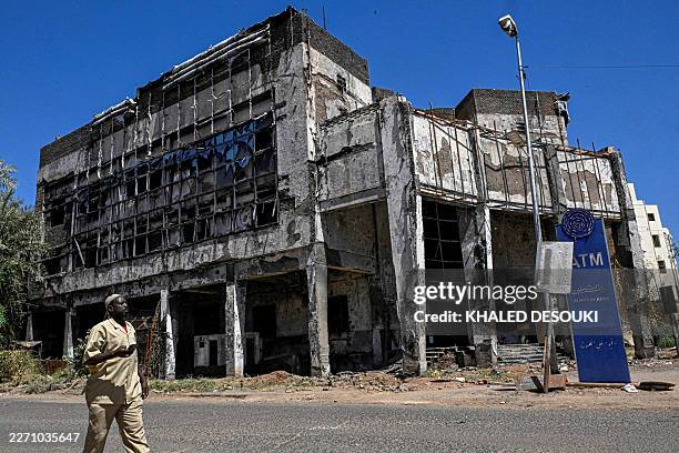 Sudanese man walks past a damaged bank building in Khartoum on April 16, 2026. Of the nearly four million people -- around half Khartoum's pre-war...