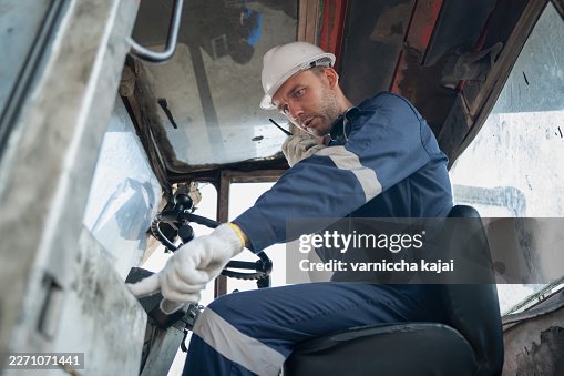 Industrial machine operator checking controls inside heavy equipment cabin Industrial machine operator checking controls inside heavy equipment cabin