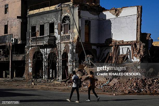 Sudanese men walk past destroyed building in the capital Khartoum on April 16, 2026. Of the nearly four million people -- around half Khartoum's...