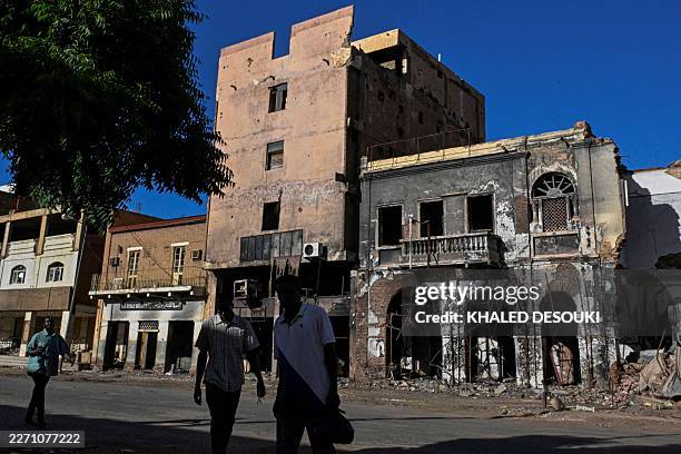Sudanese men walk past destroyed building in the capital Khartoum on April 16, 2026. Of the nearly four million people -- around half Khartoum's...