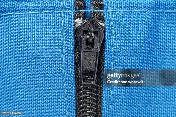 close-up of a black zipper on a blue fabric. - zipper stock pictures, royalty-free photos & images
