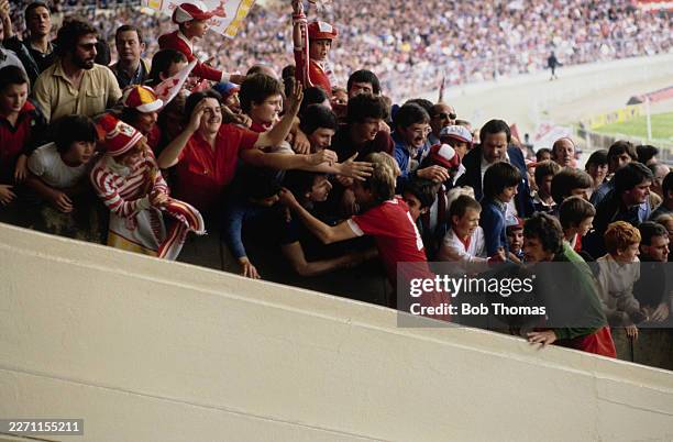 Liverpool's captain Phil Thompson and goalkeeper Ray Clemence are congratulated by fans as they climb the Wembley steps to receive the shield after...