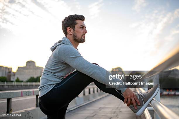 man stretching before starting run in urban environment. - precalentamiento fotografías e imágenes de stock
