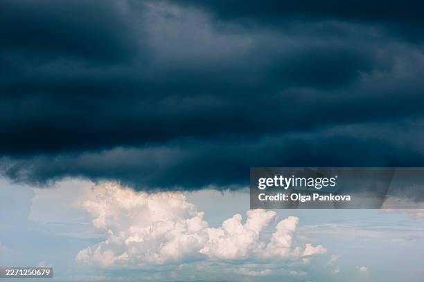 dark storm clouds gathering creating dramatic sky - calma antes de la tempestad fotografías e imágenes de stock