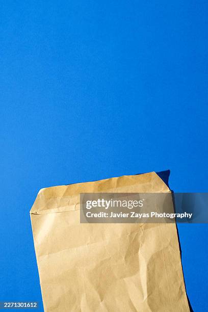 used open brown paper envelope on blue background - manila envelope stock pictures, royalty-free photos & images