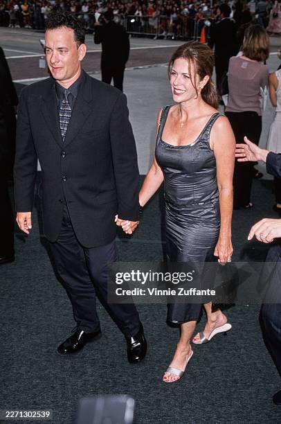 American actor Tom Hanks, wearing a black suit over a grey shirt and a patterned grey-and-black tie, and his wife, American actress and singer Rita...