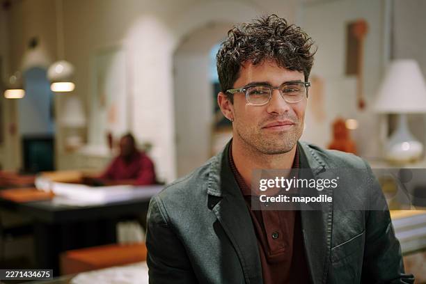 portrait créatif décontracté d’un jeune homme dans un bureau moderne avec un éclairage chaleureux et une expression réfléchie - sourire narquois photos et images de collection