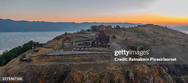 the historic 9th-century sevanavank monastery, an iconic landmark on the shores of lake sevan, armenia, is silhouetted against a spectacular golden sunrise. - sevanavank monastery stock pictures, royalty-free photos & images