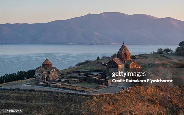 the historic 9th-century sevanavank monastery, an iconic landmark on the shores of lake sevan, armenia, is silhouetted against a spectacular golden sunrise. - sevanavank monastery stock pictures, royalty-free photos & images