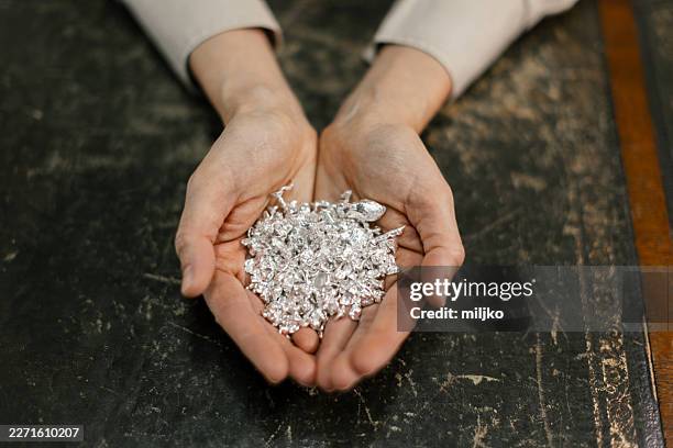 hands holding raw silver pieces on a table - silver nugget stock pictures, royalty-free photos & images