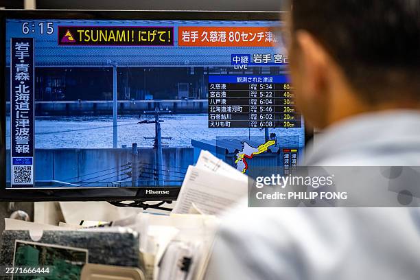 This photo shows a warning message on a screen from a live feed on NHK with tsunami alert after an earthquake hit northern Japan, in Tokyo on April...