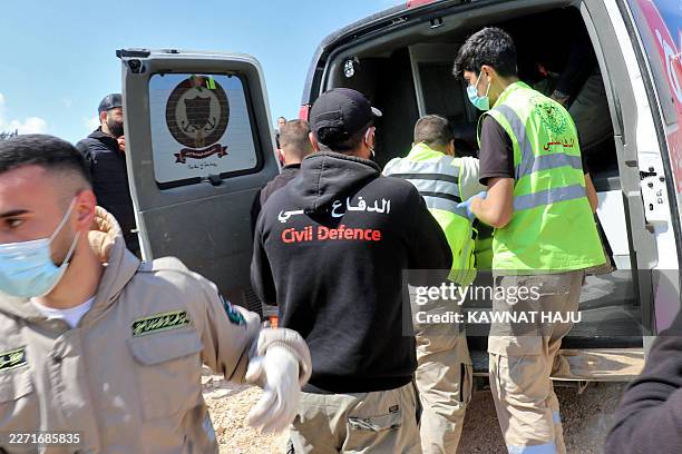 Lebanese Civil Defense personnel load the bodies of two people who were missing into an ambulance next to the bomb-damaged Qasmiyeh bridge near the...