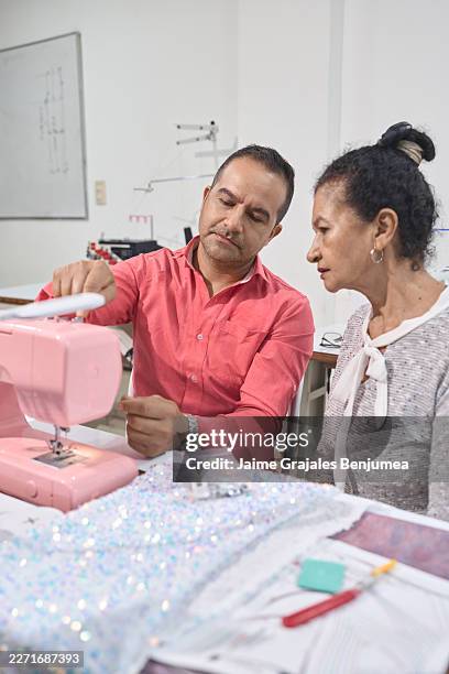 tailor instructing woman on sewing machine at workshop - threading machine stock pictures, royalty-free photos & images