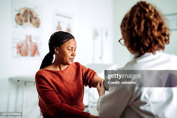 woman having blood pressure checked by female doctor - annual event stock pictures, royalty-free photos & images