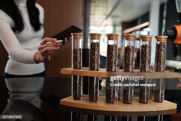 person analyzing different roasted coffee bean samples in glass tubes, preparing specialty coffee blends - smell test stock pictures, royalty-free photos & images