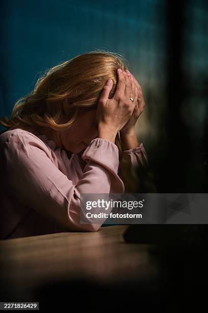 stressed woman holding her head in hands, emotional portrait of anxiety and mental health struggle - head in hands stock pictures, royalty-free photos & images