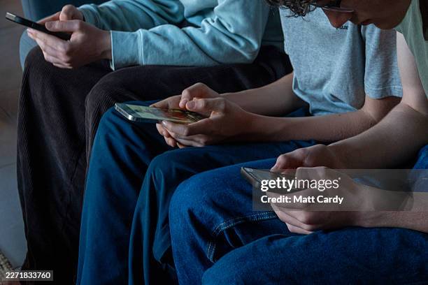 Three teenage boys look at their smartphone screens in village of St Jean d'Aulps on April 11, 2026 near Morzine, France. In the UK, a ban on social...