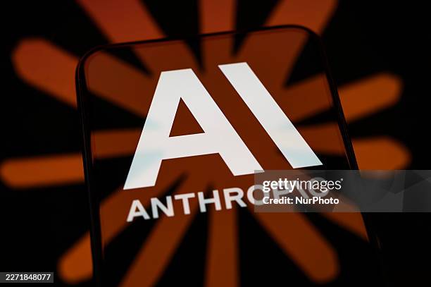 The Anthropic logo is displayed on a smartphone screen placed on a reflective surface on which the Claude logo is projected, in Creteil, France, on...