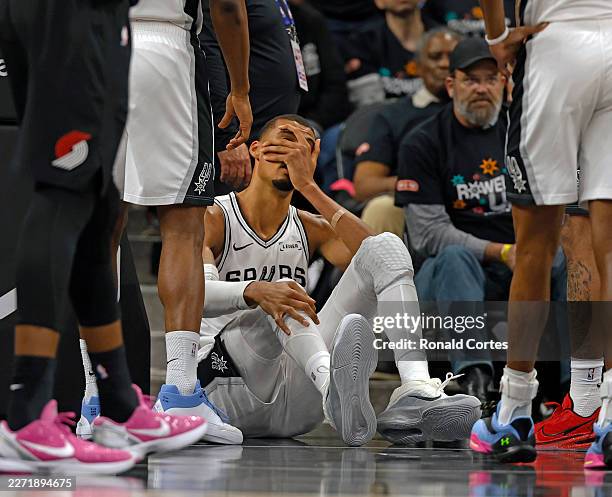 Victor Wembanyama of the San Antonio Spurs holds his head after falling to the court against the Portland Trailblazers in the first half of Game Two...