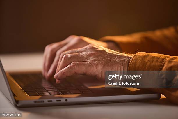 senior hands typing on laptop keyboard in warm light for remote work and technology use - warm light stock pictures, royalty-free photos & images