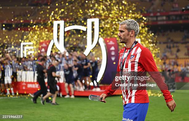 Antoine Griezmann of Atletico de Madrid walks past the podium as players of Real Sociedad celebrate with the Copa Del Rey trophy following the Copa...