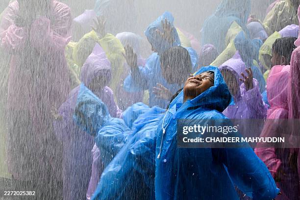 Kindergarten students react as they are sprayed with water while learning to use hoses with firefighters in Banda Aceh on April 23, 2026.