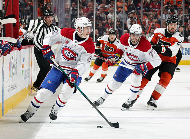 Adam Engstrom of the Montreal Canadiens skates the puck as Kirby Dach defends Noah Cates of the Philadelphia Flyers at the Xfinity Mobile Arena on...