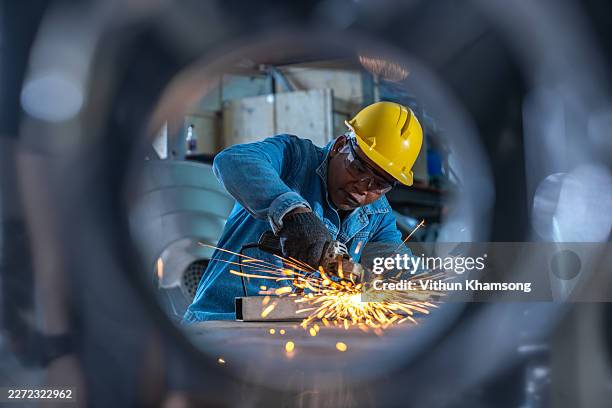 industrial worker cutting metal with sparks in factory production line - produktionsgerät stock-fotos und bilder