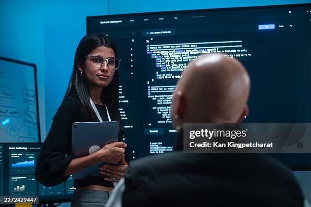 technical meeting with a woman developer explaining programming content, code review, on screen while a colleague listens collaboration in tech office. - secure content management stock pictures, royalty-free photos & images