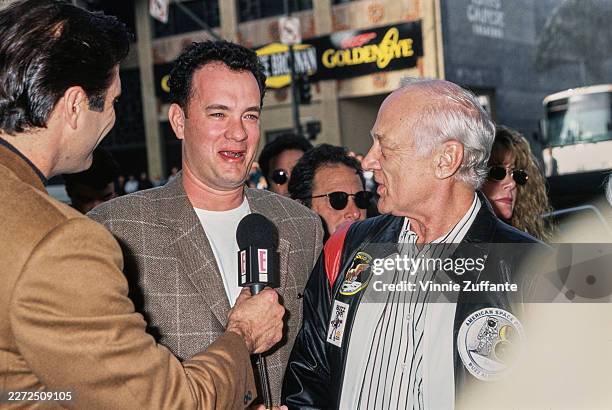 American actor Tom Hanks, wearing a checked brown blazer over a white t-shirt, and American astronaut Buzz Aldrin, who wears a black leather jacket...