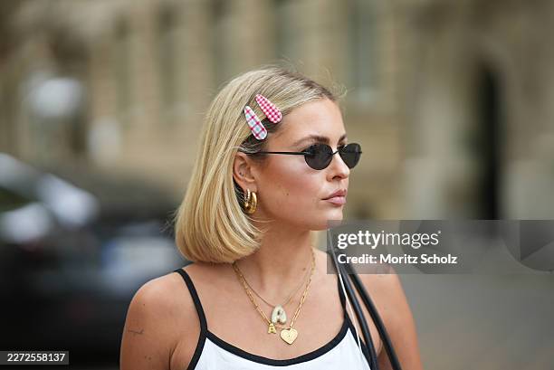 Julia Kammerer is seen wearing a white cotton tanktop from JJXX; oval black sunglasses with dark tinted lenses from Vehla; wired headphones from...