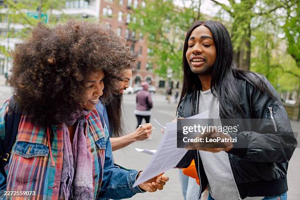 two young activists looking at a document and talking during a public rally - petition stock pictures, royalty-free photos & images