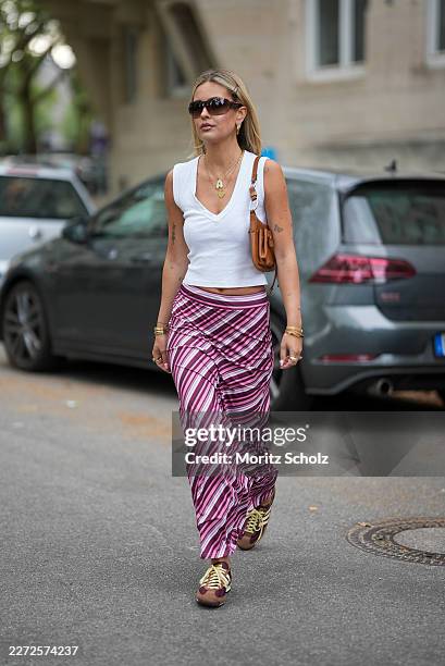 Julia Kammerer is seen wearing a white cotton sleeveless tank top with a ribbed v neckline from Zara; a pink, purple and white horizontal striped...