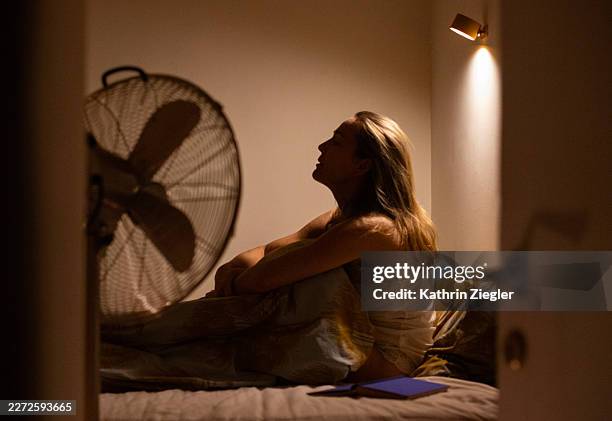 sleepless woman sitting up in bed at night - ola de calor fotografías e imágenes de stock