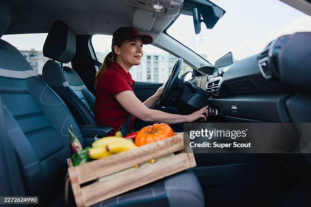 female delivery driver starting car with fresh vegetables ready for delivery - flatten the curve stock pictures, royalty-free photos & images