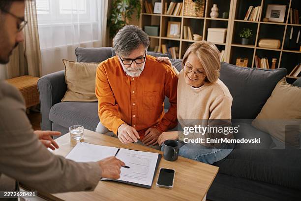 couple mature discutant d’assurance vie avec un conseiller financier à domicile - testament photos et images de collection