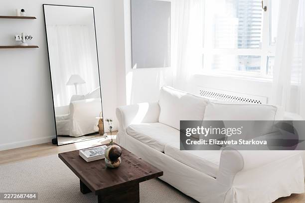 bright scandinavian living room interior with cozy grey sofa, wooden coffee table, and large window letting in soft natural daylight. - einfaches leben stock-fotos und bilder