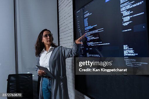 Professional Woman Developer Pointing at Source Code During AI and Big Data Project Meeting in Tech Office meeting room at night. Professional Woman Developer Pointing at Source Code During AI and Big Data Project Meeting in Tech Office meeting room at night.