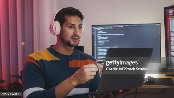 young latin man software developers using computer to write code app program for ai technology and video call at desk with multiple screens work at home office night. programmer development concept. - api developer stock pictures, royalty-free photos & images
