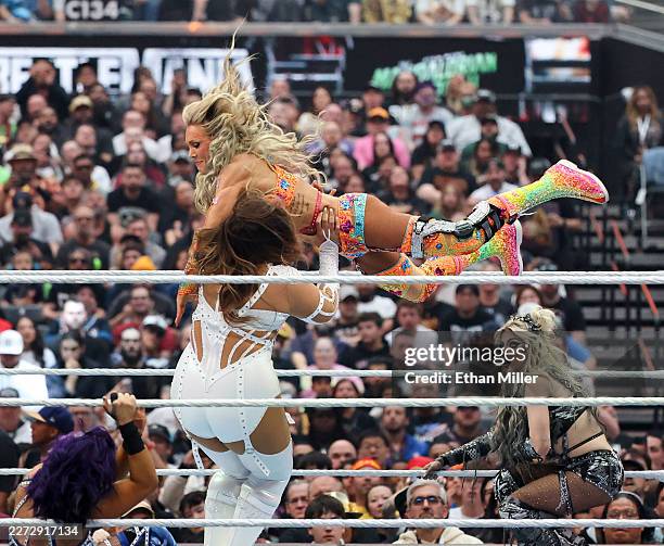 Charlotte Flair jumps off the ropes at Nia Jax as Alexa Bliss looks on during the WWE Women's Tag-Team Championship Fatal 4-Way match with Brie...